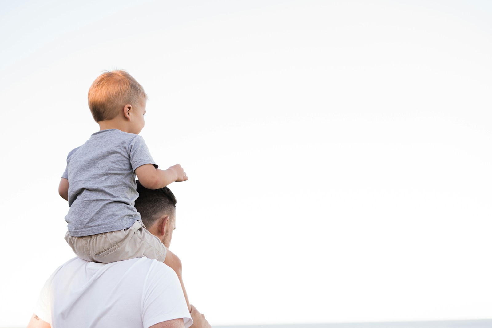 Man in white shirt carrying boy