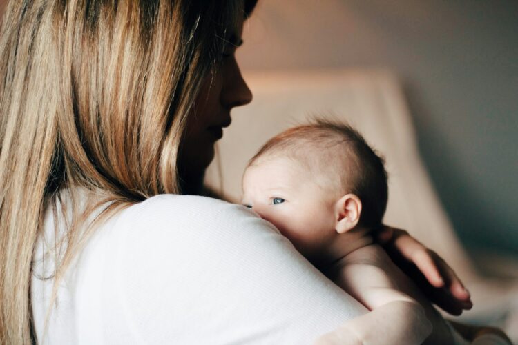 Woman in white shirt carrying baby