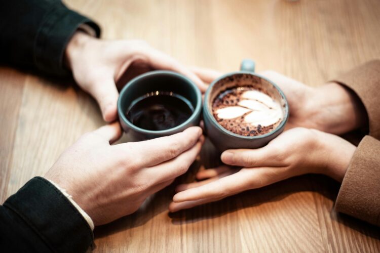 Two person holding ceramic mugs with coffee