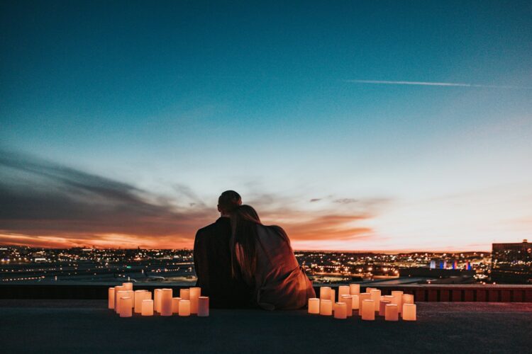 Couple sitting on the field facing the city