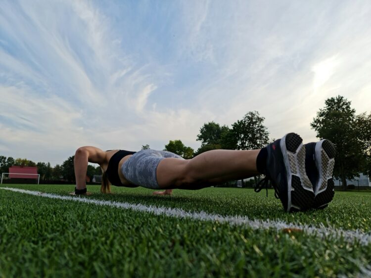 A woman is doing push ups on the grass