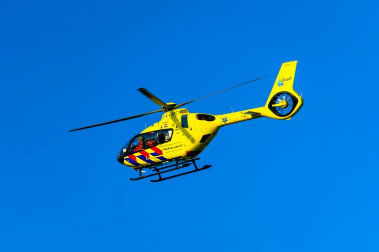 A yellow helicopter flying through a blue sky