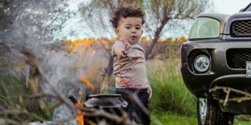A little boy standing next to a black truck