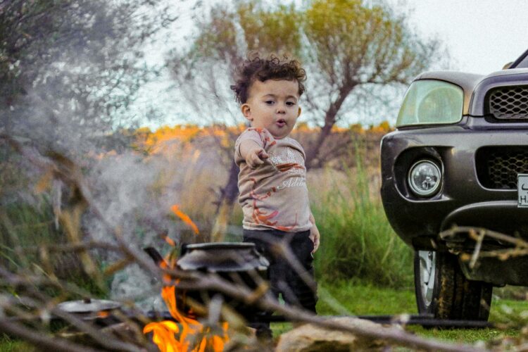 A little boy standing next to a black truck