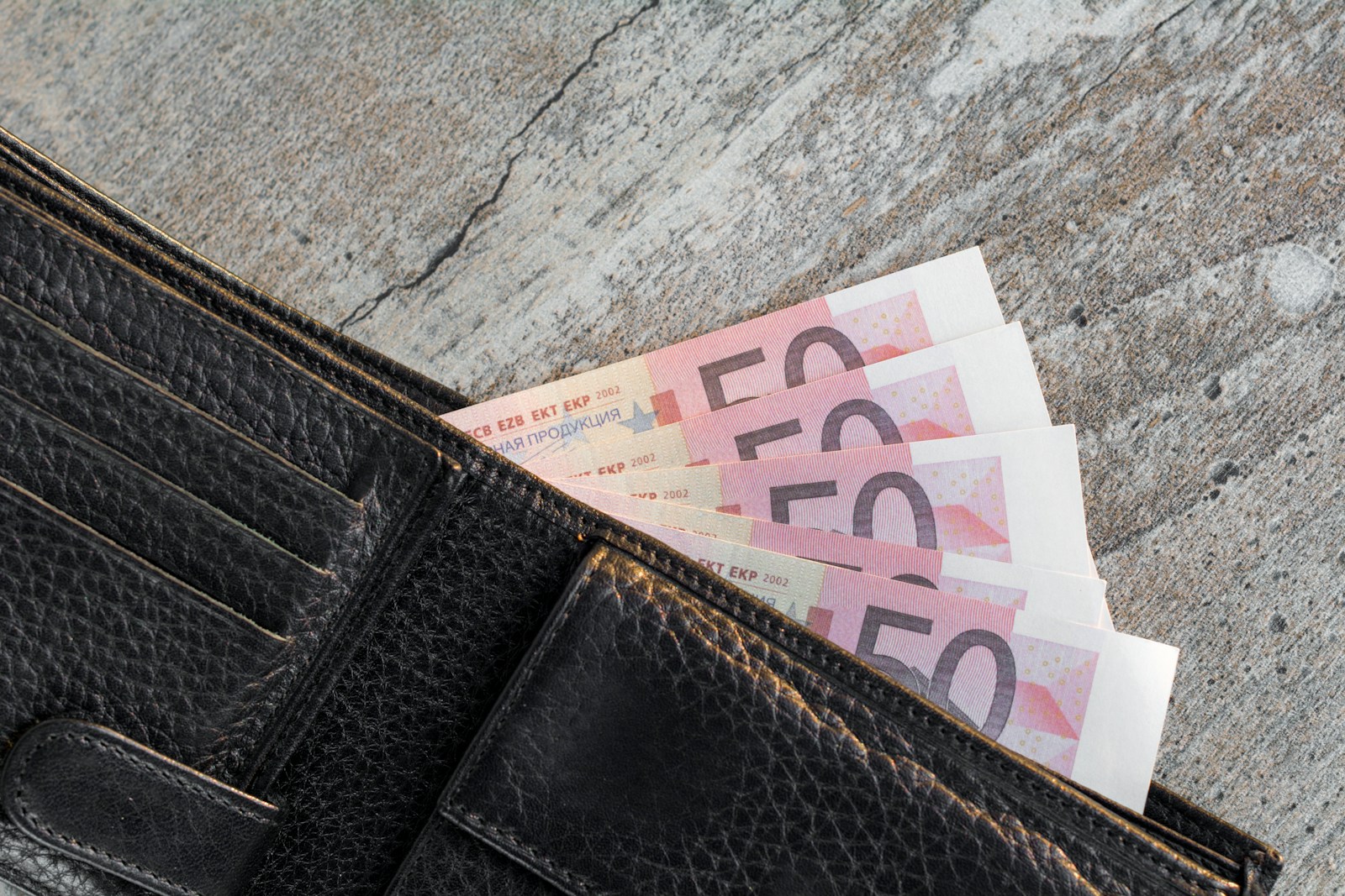 A wallet with a bunch of money sticking out of it