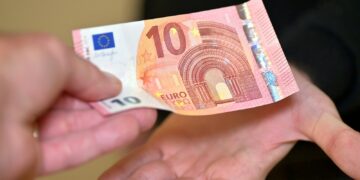 a person holding a ten euros bill in their hands