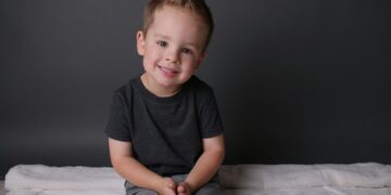 boy in black crew neck t-shirt sitting on white bed