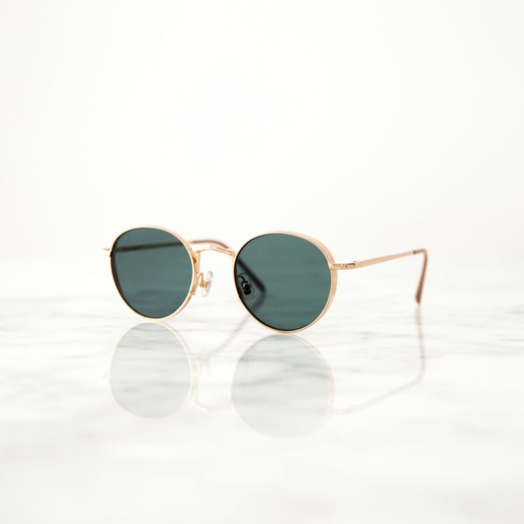 Gold colored framed hippie sunglasses on white surface
