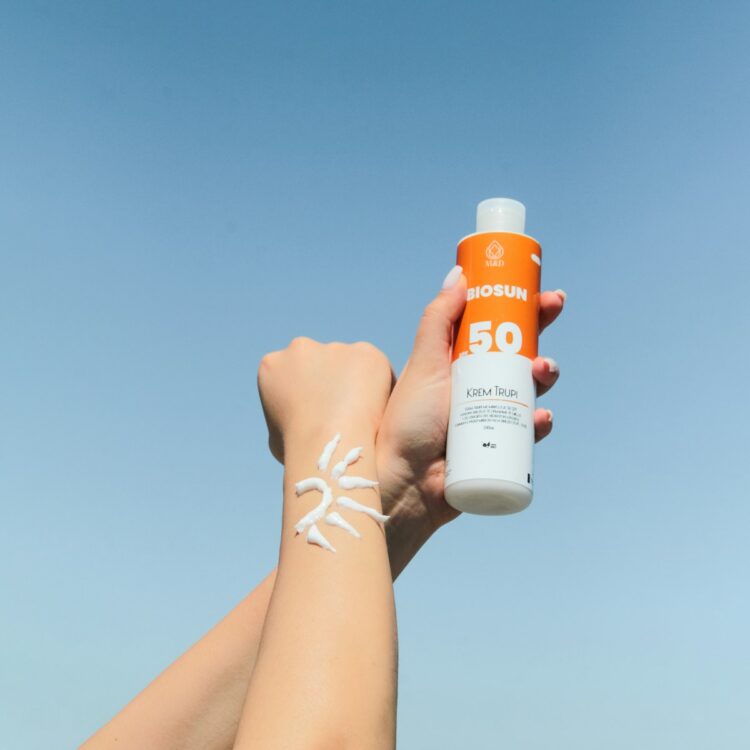 A person holding a bottle of sunscreen in their hand