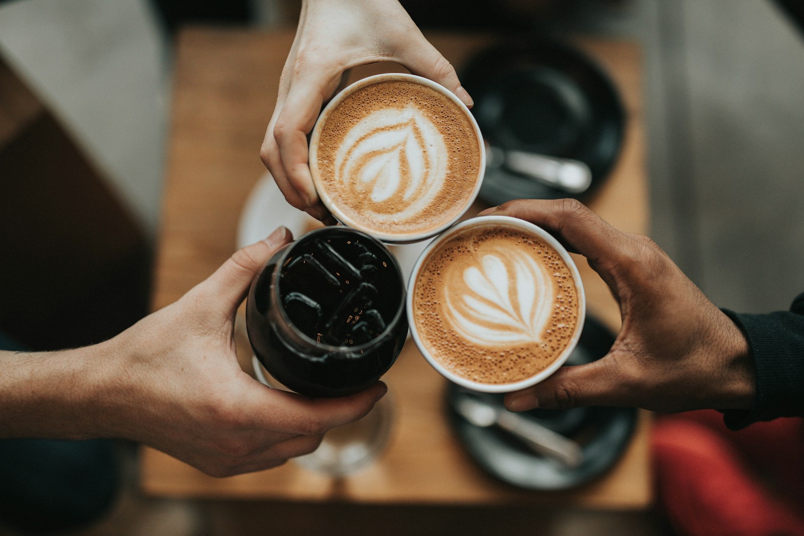 Three person holding beverage cups