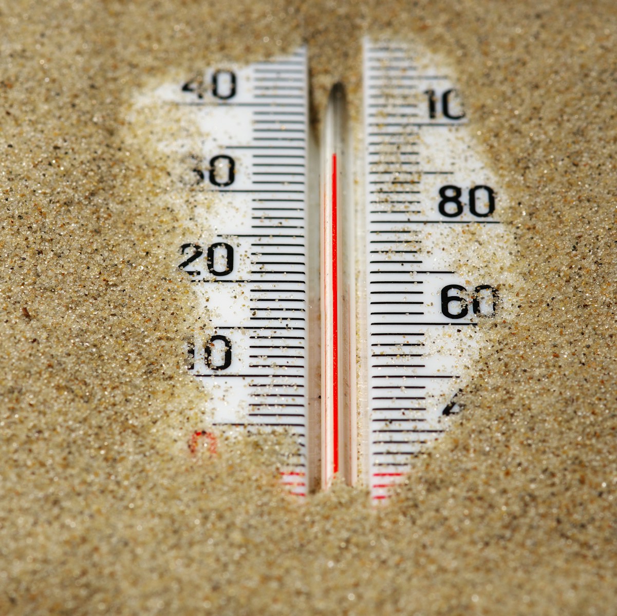 A close up of a thermometer in the sand