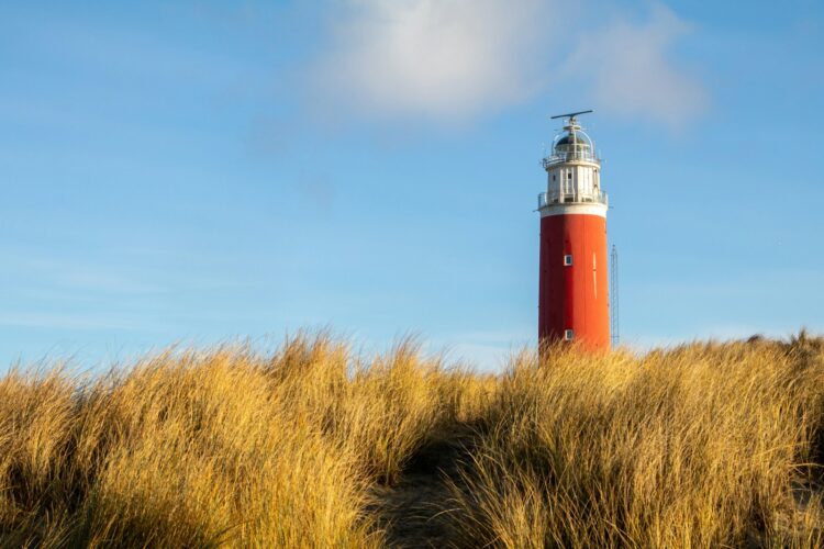 Red and white lighthouse under blue sky during daytime
