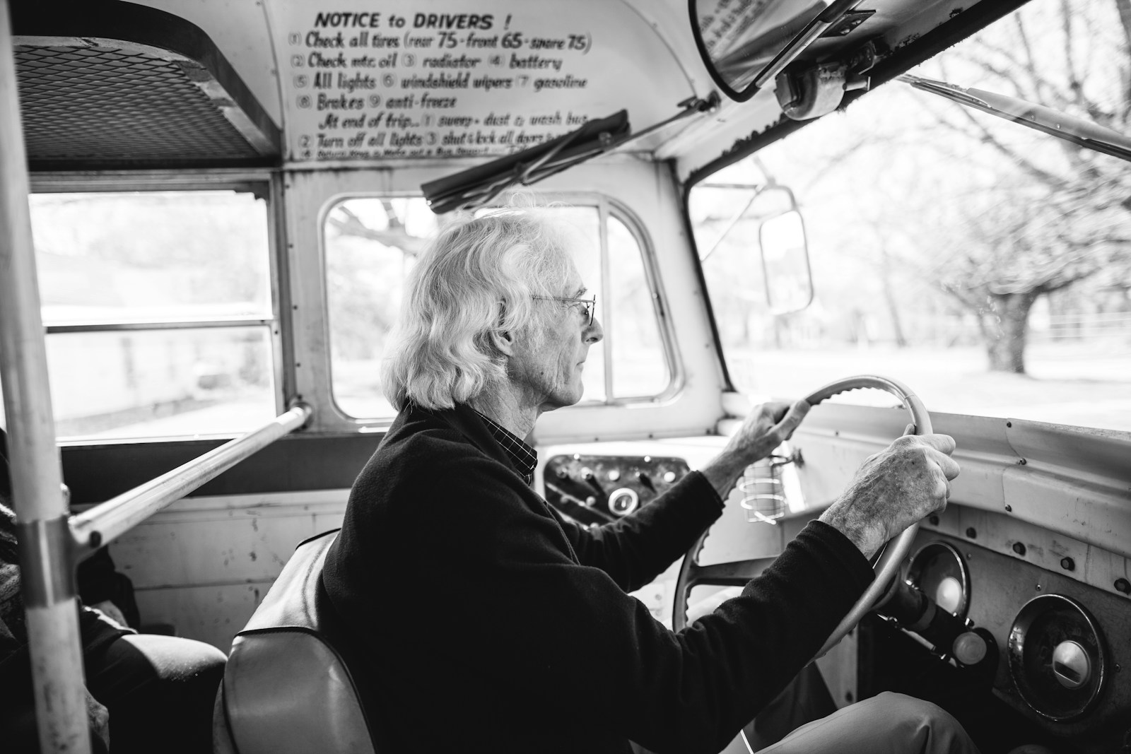 Grayscale photo of man driving vehicle