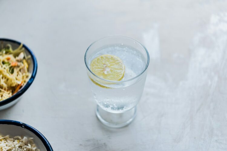 A glass of water with a lemon slice on top