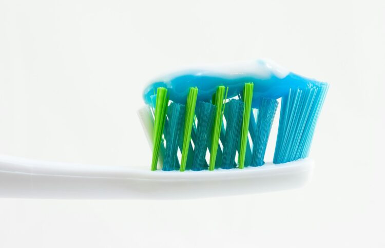 White blue and green toothbrush with blue toothpaste