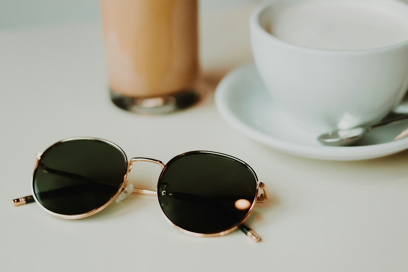 Silver framed aviator style sunglasses on white ceramic saucer
