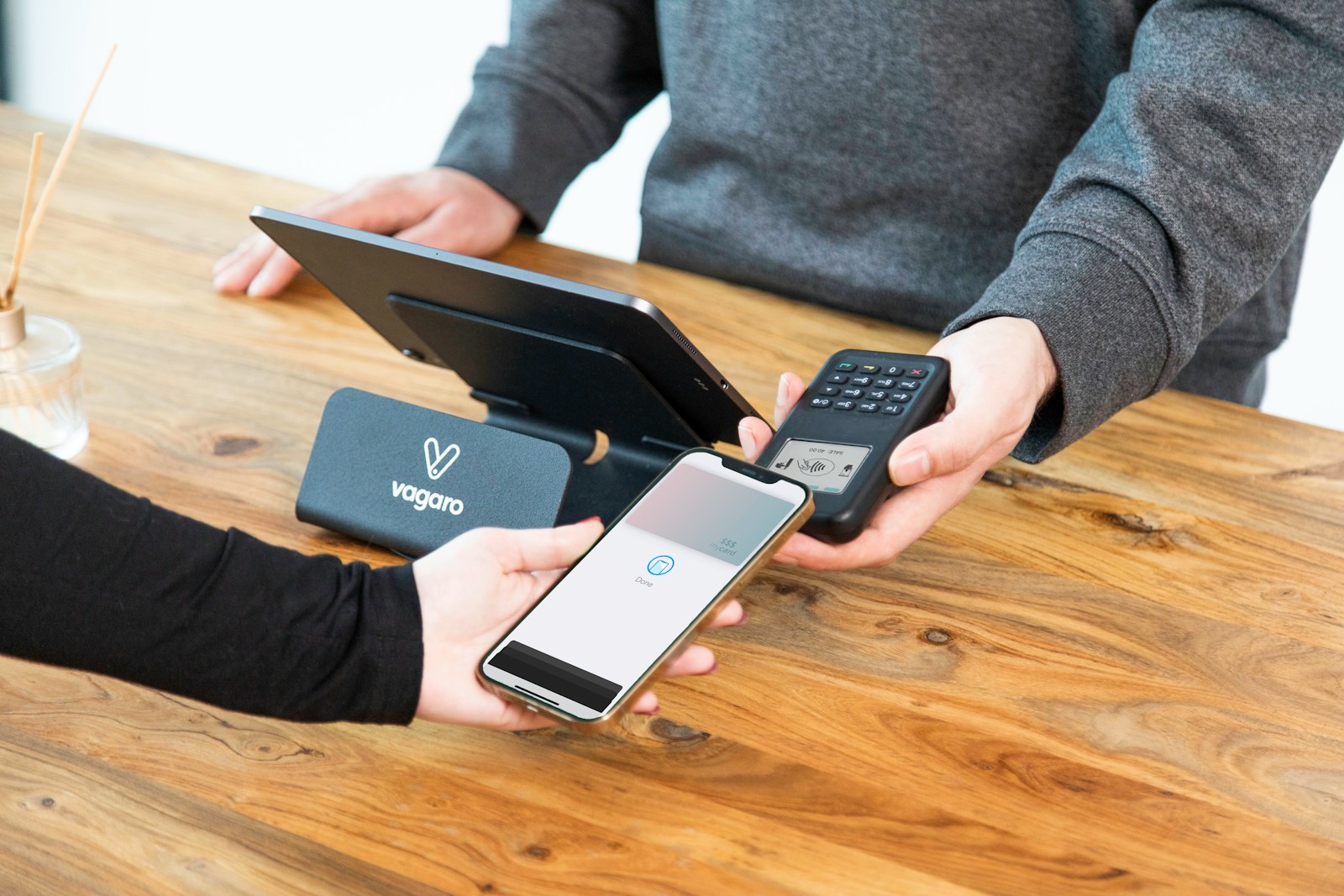 A person holding a cell phone and a laptop on a table