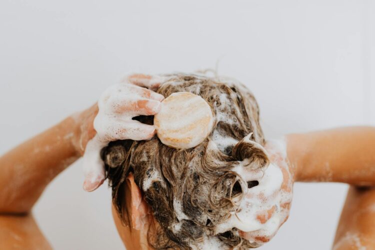 Close up of a person washing their hair with soap bar and foam focusing on hands and hair
