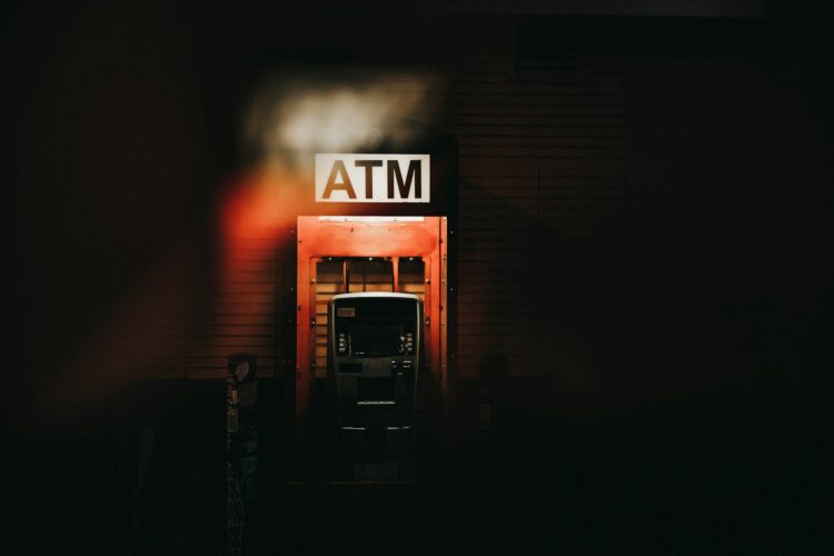 A building with a atm sign lit up at night