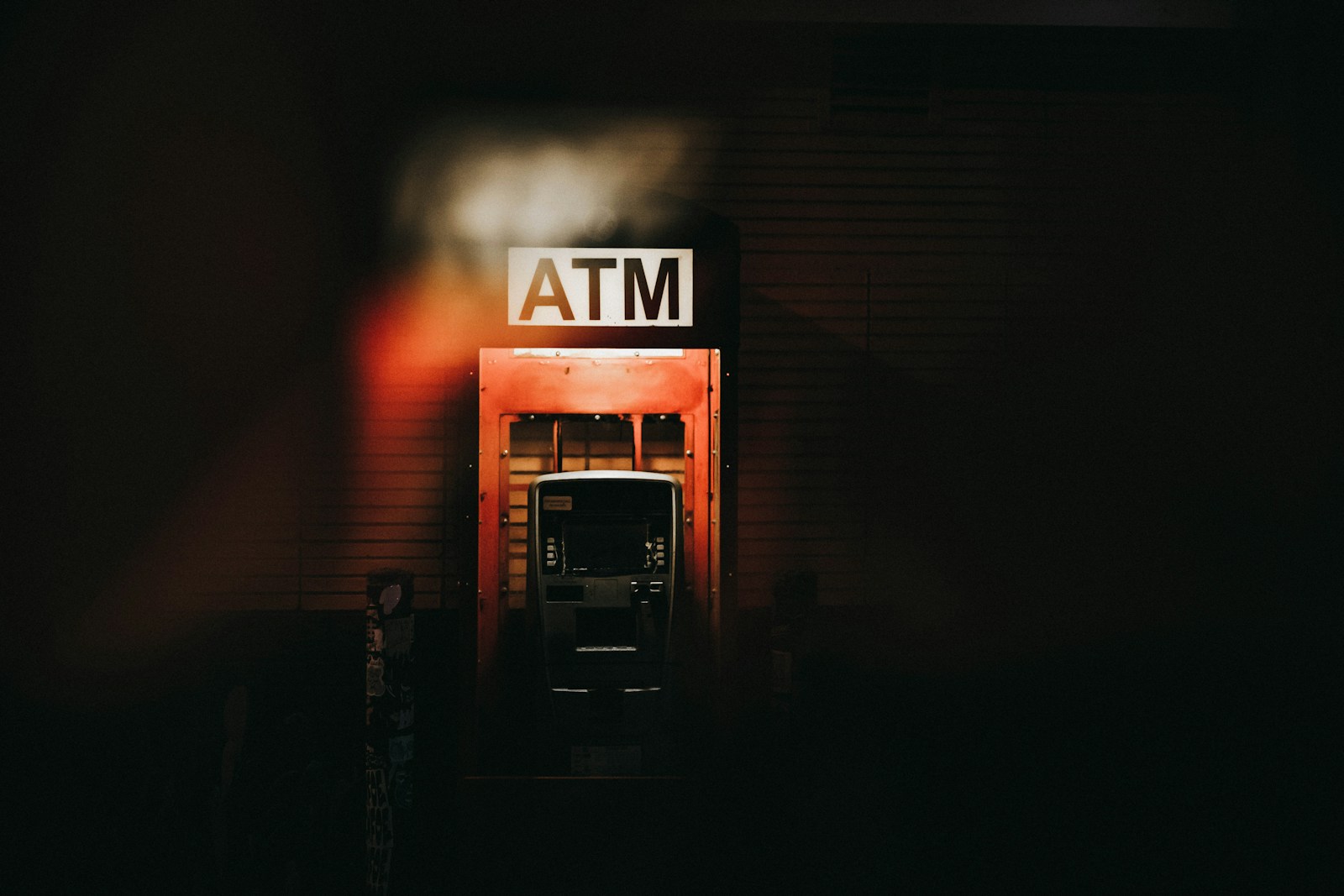 A building with a atm sign lit up at night