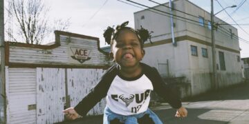 girl standing near concrete building under gray sky