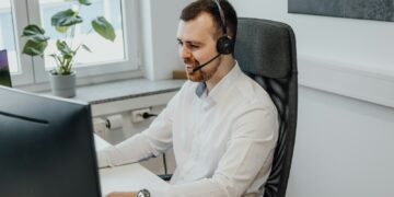 a man wearing a headset sitting in front of a computer