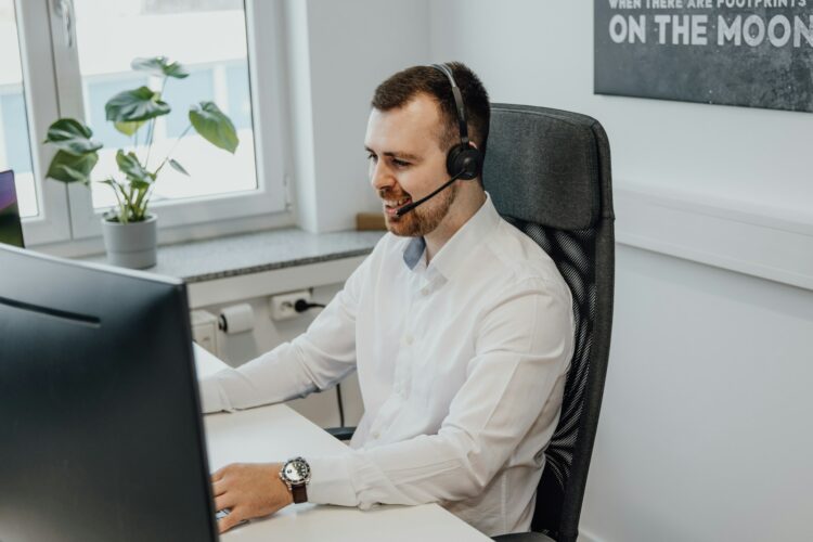 A man wearing a headset sitting in front of a computer