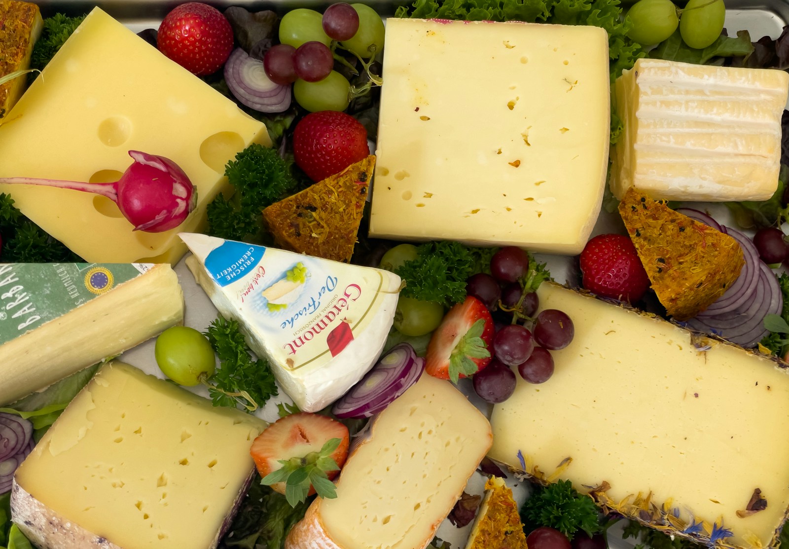 A variety of cheeses and fruits are arranged in a tray