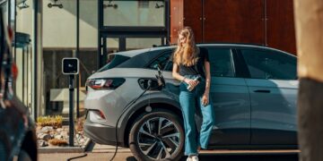 a woman standing next to a blue car