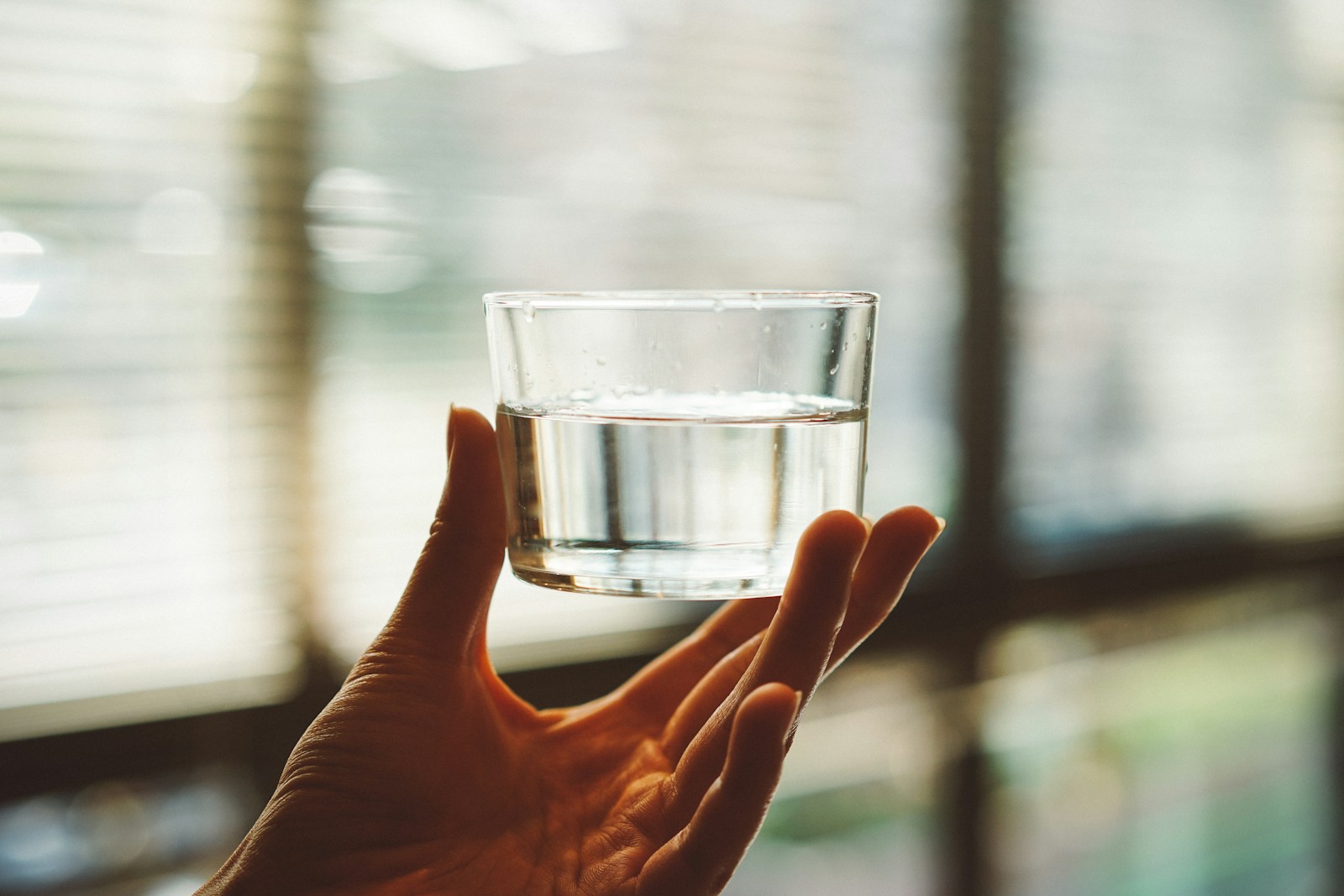 Person holding clear glass cup with half filled water