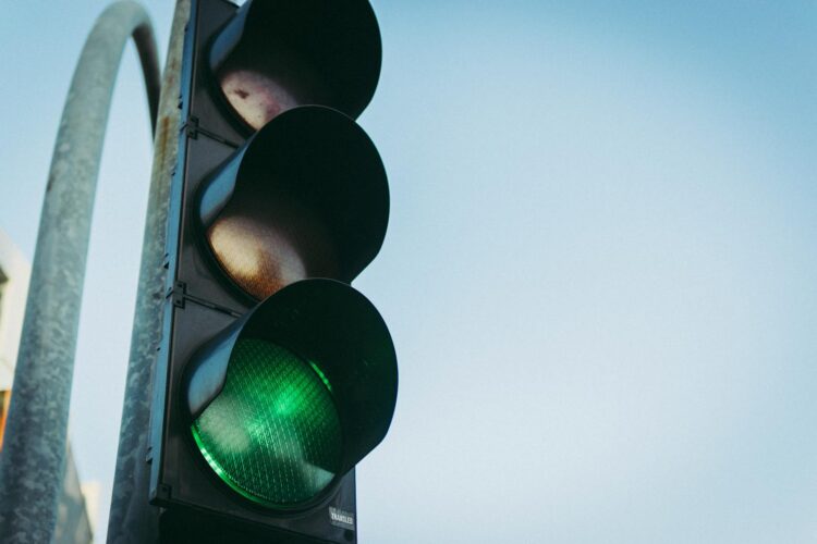 Close up of a green traffic light against a clear blue sky symbolizing go and safety