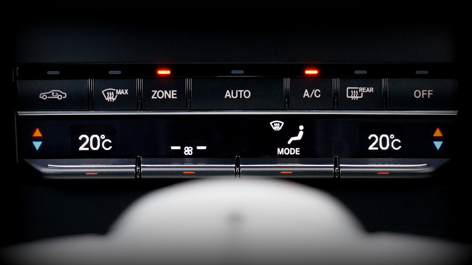 Close up image of a car's climate control panel with digital temperature display.