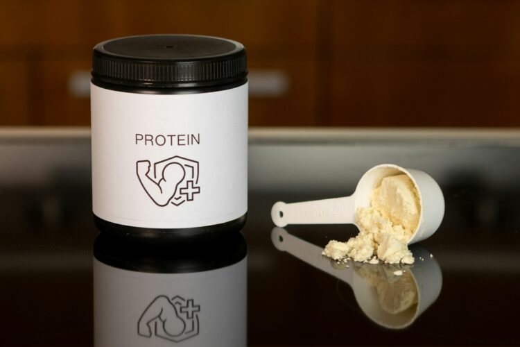 A container of protein powder next to a spoon