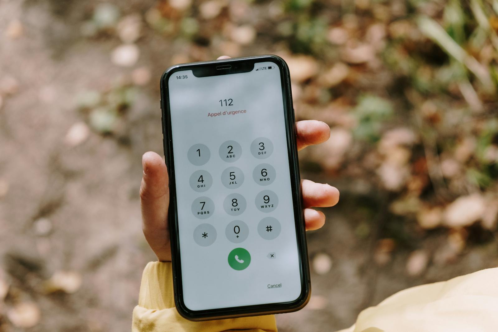 Close up of emergency number dialed on smartphone held outdoors emphasizing mobile technology's role in safety.