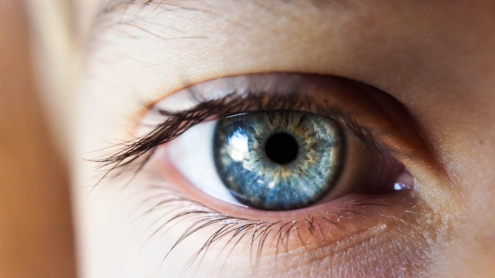 Person opening his right eye with blue iris