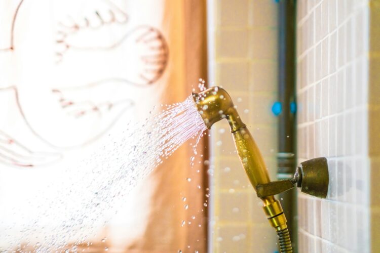 A shower head spraying water onto a tiled wall