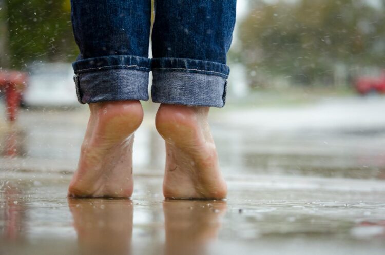 Close up of bare feet on a wet pavement capturing calm and connection with nature