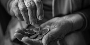 A black and white photo of a person holding a handful of coins