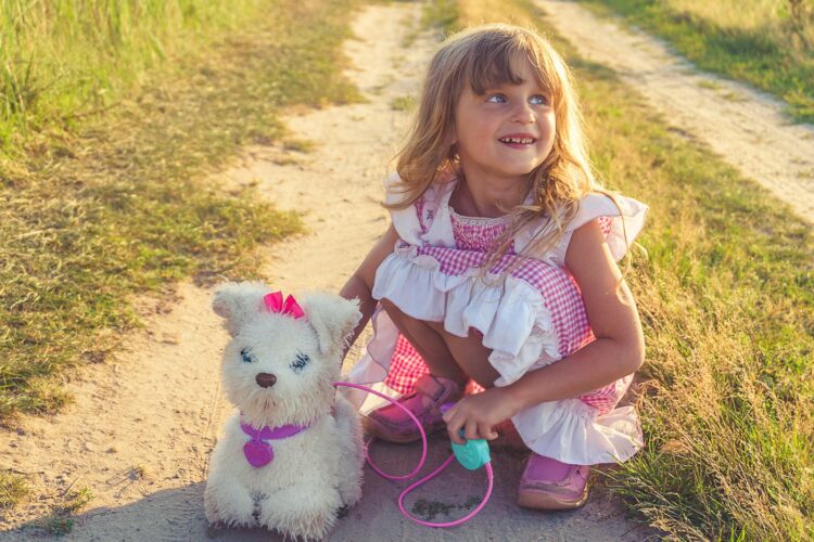 Girl in pink and white dress holding white dog plush toy