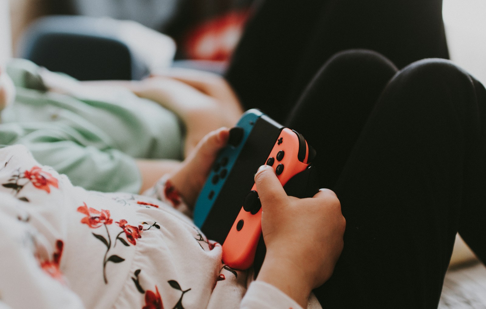 Person holding blue and orange joy con controller
