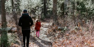 man in black jacket and black pants standing in the middle of forest during daytime