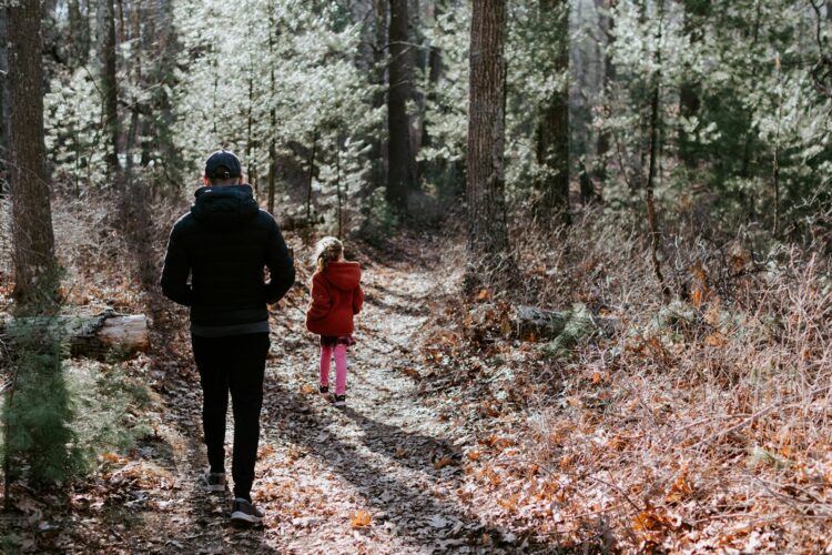 Man in black jacket and black pants standing in the middle of forest during daytime
