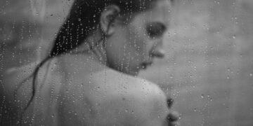 a black and white photo of a woman in the rain