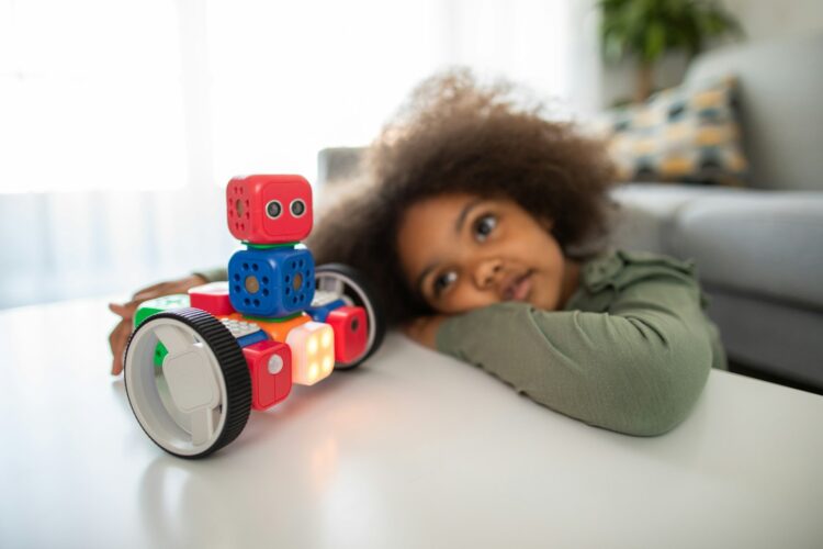 Boy lying on bed playing with red and blue toy truck