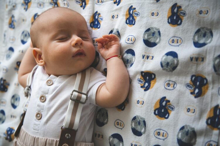 A baby sleeps peacefully on a patterned blanket