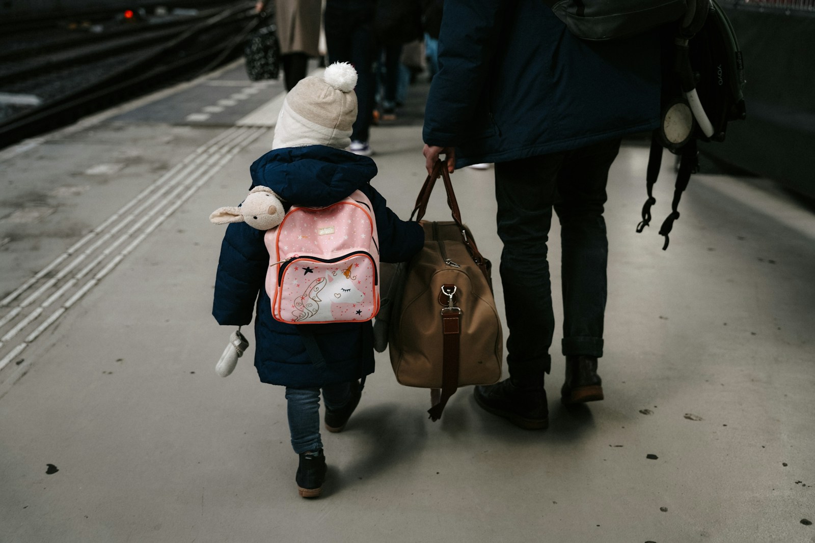 A child walks with a person holding luggage