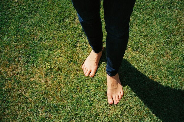Person in blue denim jeans standing on green grass field