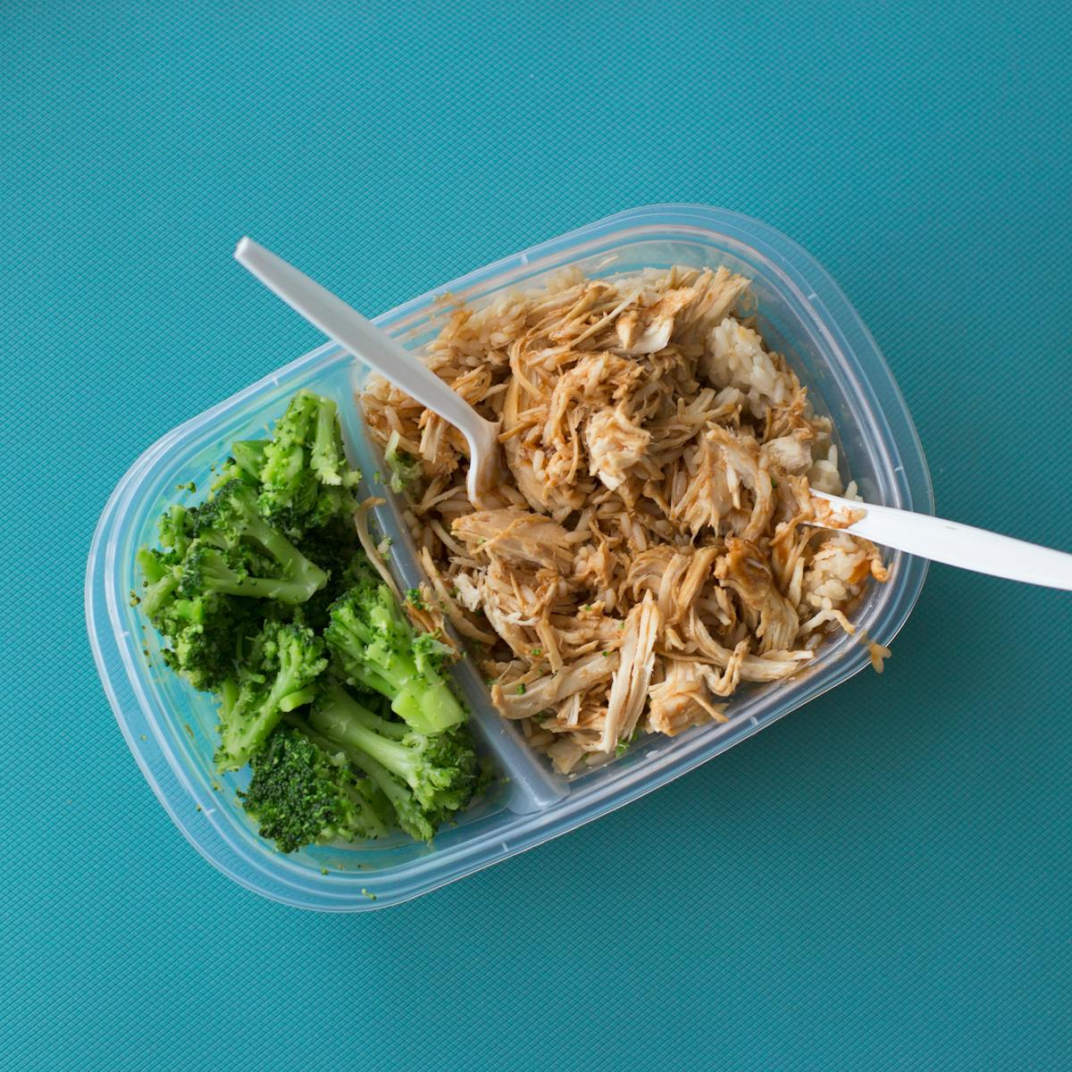 Delicious packed lunch with shredded chicken rice and broccoli in a tupperware container