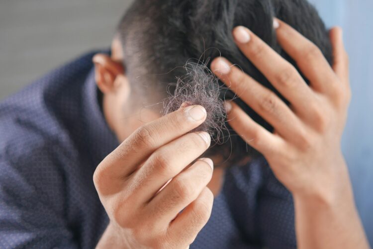 A man is combing his hair with his hands