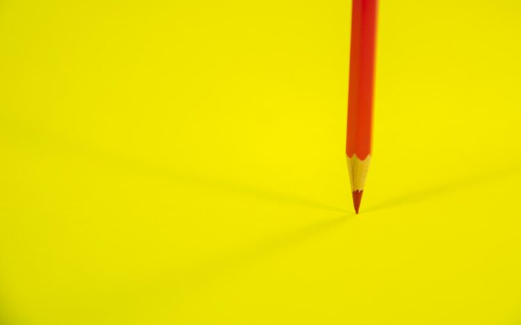 Red pencil on yellow surface